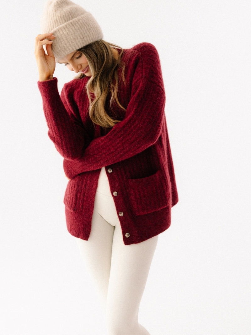 Beżowa damska czapka z wełny alpaki i jagnięcej z naturalnych włókien i z elastycznym ściągaczem - outfit z długim bordowym kardiganem z wełny i białymi legginsami sportowymi