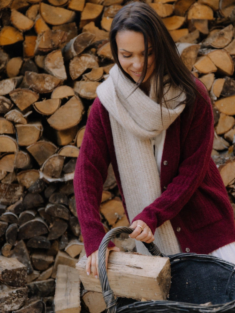 Długi beżowy szalik z wełny alpaki i jagnięcej owinięty wokół szyi w outficie z długim bordowym swetrem z wełny alpaki