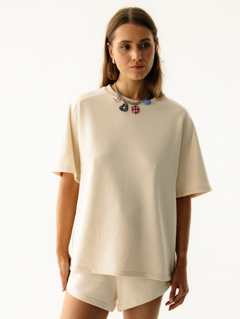 Modelka w kremowym zestawie Coast - koszulka z krótkim rękawem i szorty w kolorze Almond Milk